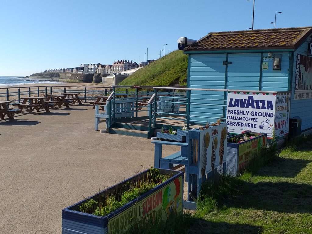 Wooden coffee kiosk with planters, overlooking a beach